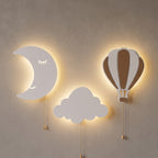 La lune allumée avec le nuage et la montgolfière, sur un mur clair, le soir.