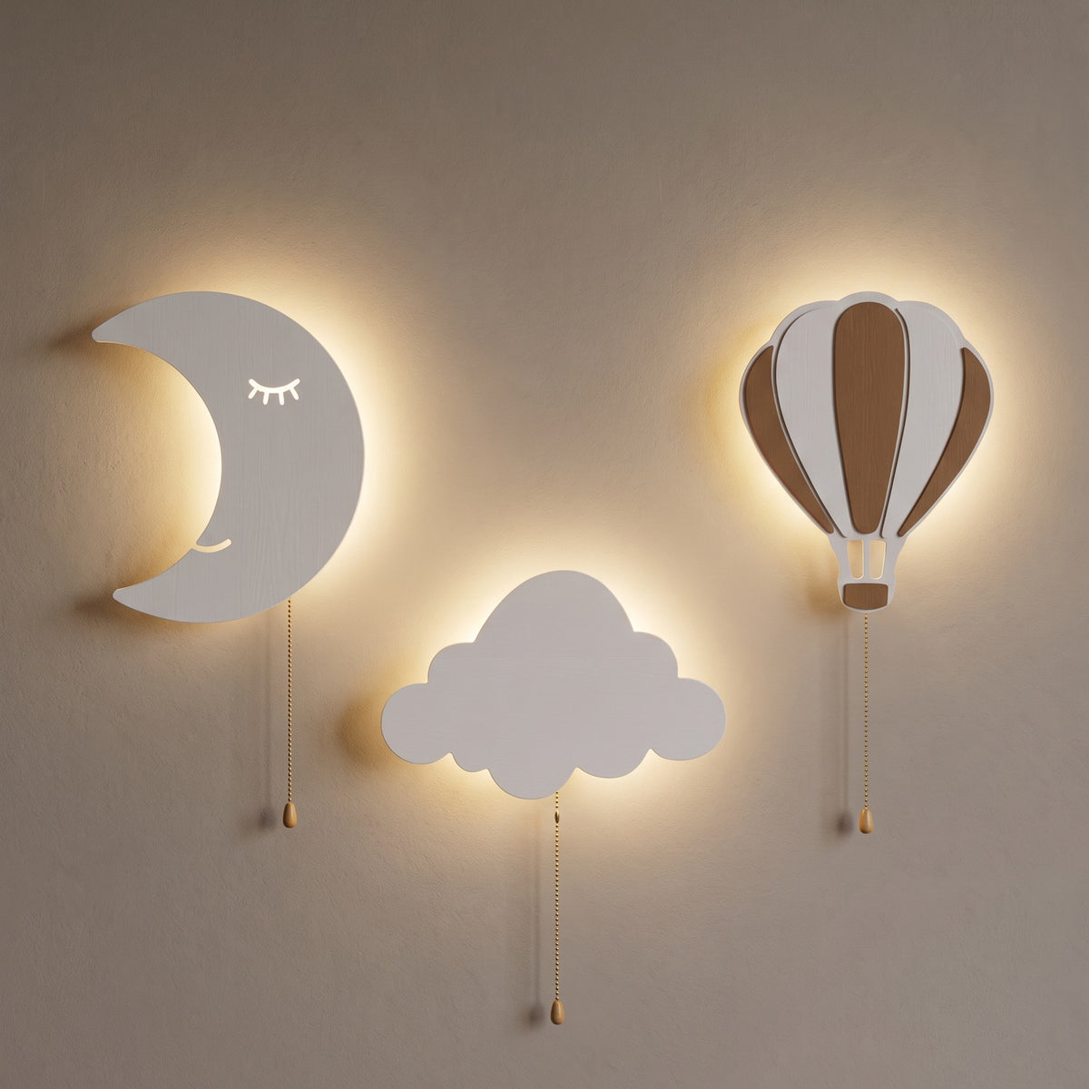 Les trois lampes allumées sur un mur clair, le soir, avec leur halo blanc chaud.
