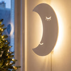 La lune allumée au mur, son visage endormi éclairé par derrière.